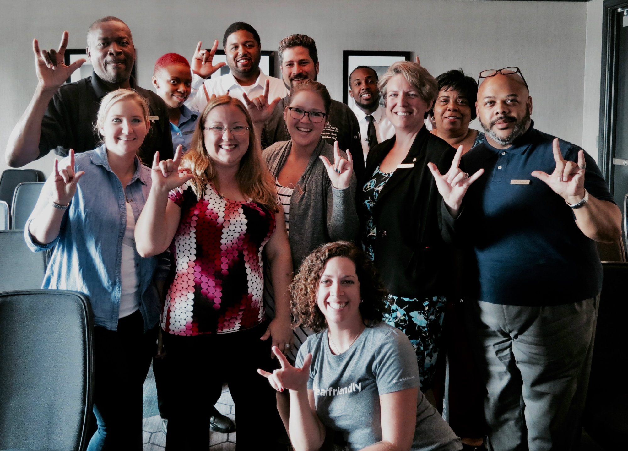 Hotel staff pose for a picture with their hands up signing "I LOVE YOU"
